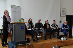 In the photo, the Dean, Prof. Nicole Burzan, is standing next to the lectern on the stage. Prof. Bernd Sommer, Prof. Maximiliane Wilkesmann, Prof. Jürgen Howaldt, Prof. Dorothee Gronostay, Prof. Mona Motakef, Prof. Martina Brandt sit in a semi-circle on the stage.