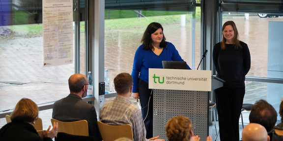 Mona Motakef und Katharina Hoppe hinter dem Rednerpult vor dem klatschenden Publikum