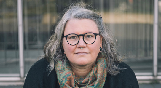 Das Foto zeigt Dr. Anike Krämer, die auf einer Bank sitzt.