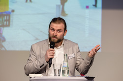 Eine Person steht an einem Rednerpult mit Mikrofon in der Hand