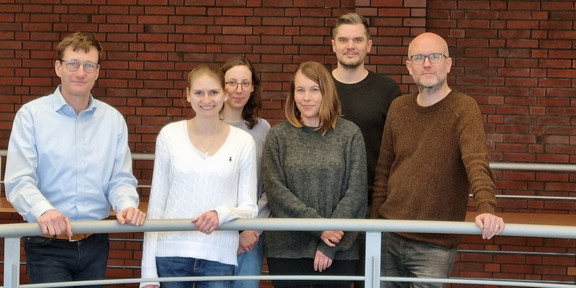 Six people stand on the gallery in the library in the social research centre