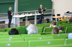 Zwei Wissenschaftler stehen m Hörsaal vor und führen eine Session durch