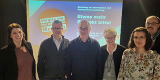Ein Gruppenfoto vor einer Projektion des Veranstaltungslogos. Auf dem Bild zu sehen sind von rechts nach links: Anne Herr (Präventionsnetzwerk #sicher im Dienst des Landes NRW), Jens Maylandt (sfs), Dr. Klaus Kock (sfs), Jutta Reiter (DGB), Ninja Ulland (sfs), Dirk Eßer (Unfallkasse NRW)  