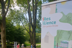 Climate oasis in Blücherpark in Dortmund's Nordstadt with seating under trees and a sign from the "iResilience" project