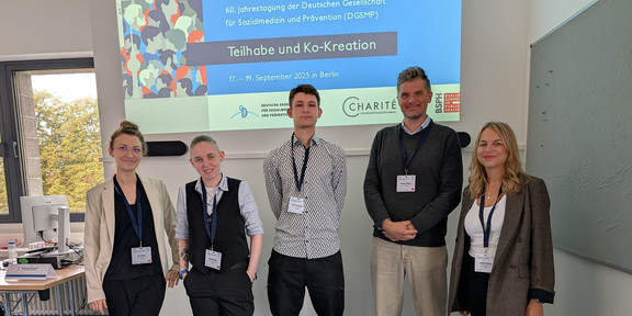 Photo: Five people standing in front of a presentation on a screen