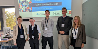 Photo: Five people standing in front of a presentation on a screen