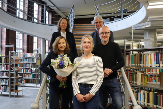 Photo: Five people are standing on a staircase for a group photo.