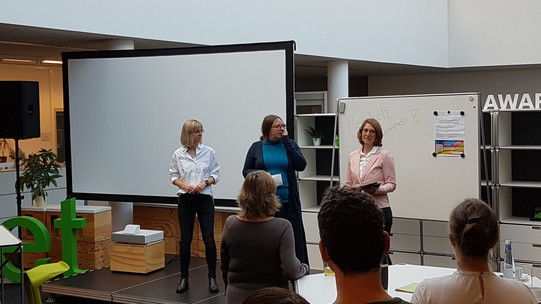 Auf dem Foto stehen die dezentralen Gleischstellungsbeauftragten Lea Zindel, Lisa-Marian Schmidt und Miriam Schad (von links nach rechts) vor den Teilnehmenden des Gleichstellungstages und begrüßen diese.