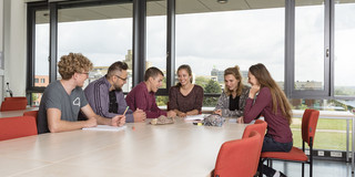 Foto: Sechs Studierende sitzen an einem Tisch und lernen zusammen