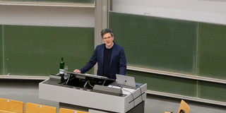 Das Foto zeigt Prof. Dr. Bernd Sommer bei seiner Antrittsvorlesung. Er steht unten am Rednerpult und schaut ins Auditorium.