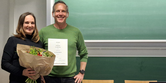 Cornelius Schubert überreicht Anita Tisch die Ernennungsurkunde zur Honorarprofessorin an der Fakultät Sozialwissenschaften und einen Blumenstrauß.