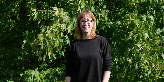 Mitarbeiterin Yvonne Zech steht vor einem Baum