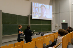 The photo shows Prof. Christoph Strünck from the Research Society for Geronotoligics. He speaks a greeting via video message for Prof. Monika Reichert, who is looking at the screen with Prof. Martina Brandt and the guests present.