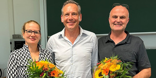 Auf dem Foto ist das neu gewählte Dekanat der Fakultät Sozialwissenschaften zu sehen. Links steht die wiedergewählte Prodekanin Forschung, Prof. Dr. Martina Brandt, mit einem Blumenstrauß in der Hand. In der Mitte steht der neugewählte Dekan, Prof. Dr. Cornelius Schubert. Rechts neben ihm steht der wiedergewählte Studiendekan, Dr. Arne Niederbacher, der ebenfalls einen Blumenstrauß in der Hand hält.