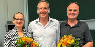 The photo shows the newly elected Dean's Office of the Department of Social Sciences. On the left is the re-elected Vice Dean of Research, Prof. Martina Brandt, with a bouquet of flowers in her hand. In the middle is the newly elected Dean, Prof. Cornelius Schubert. To his right is the re-elected Dean of Studies, Dr. Arne Niederbacher, who is also holding a bouquet of flowers.