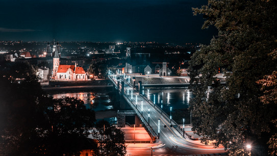 Blick auf eine Stadt bei Nacht von einem Hügel aus