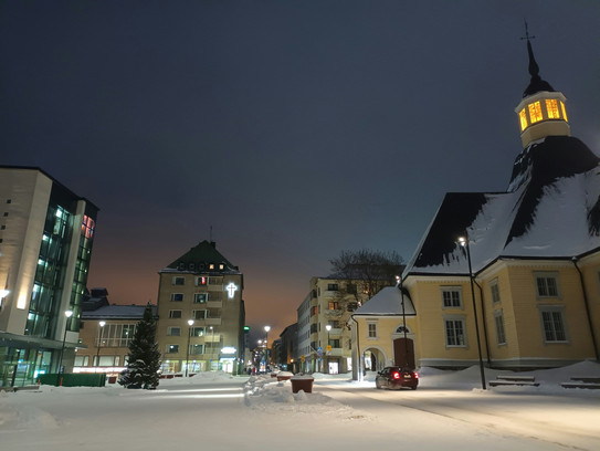 Verschneite Straße mit Gebäuden und einem Glockenturm im Hintergrund