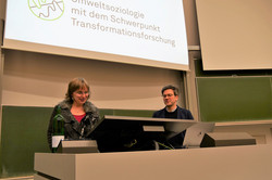 Das Foto zeigt Prof. Dr. Nicole Burzan, Dekanin der Fakultät Sozialwissenschaften, zusammen mit Prof. Dr. Bernd Sommer. Im Hintergrund ist ein Ausschnitt der Präsentation zur Antrittsvorlesung zu sehen.