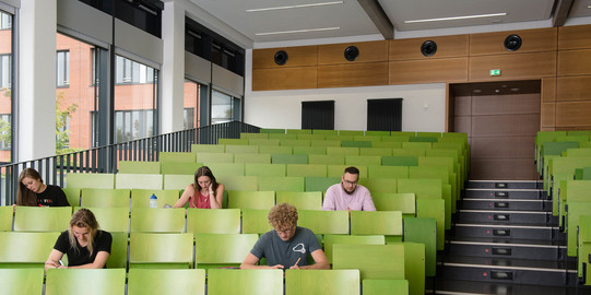 Studierende sitzen im Hörsaal Vier Studierende sitzen im Hörsaal.