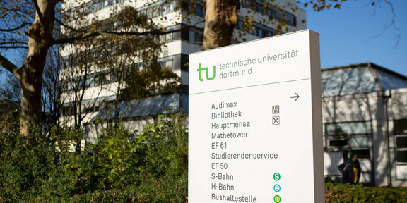 Wegweiser Wegweiser auf dem Campus Nord, im Hintergrund Bäume und ein Gebäude.
