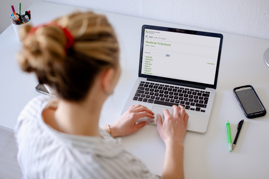 Foto einer Frau, die auf einen Laptop blickt.