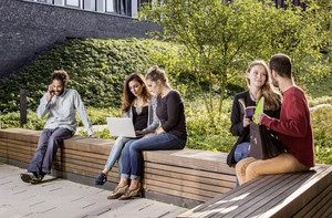 Students sitting on a seating area behind the new physics building.