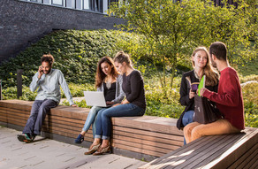 Studierende sitzen auf einer Sitzgruppe hinter dem neuen Physikgebäude