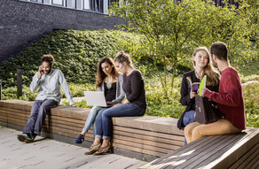 Students sitting on a seating area behind the new physics building.
