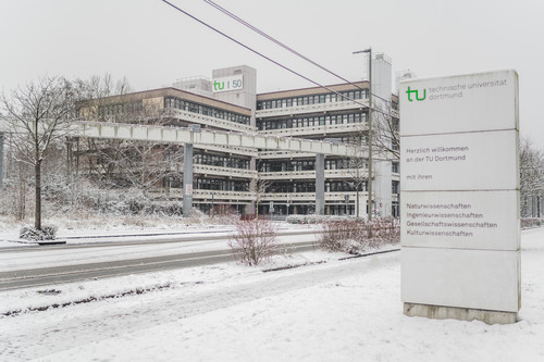Schild mit Aufschrift Herzlich willkommen an der TU Dortmund, im Hintergrund das verschneite EF50-Gebäude.