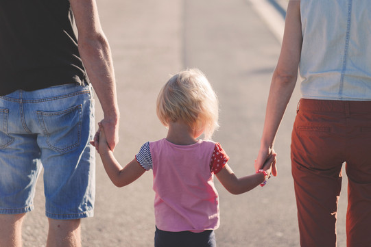 Familie_01 Erwachsene halten ein Kind rechts und links an den Händen.